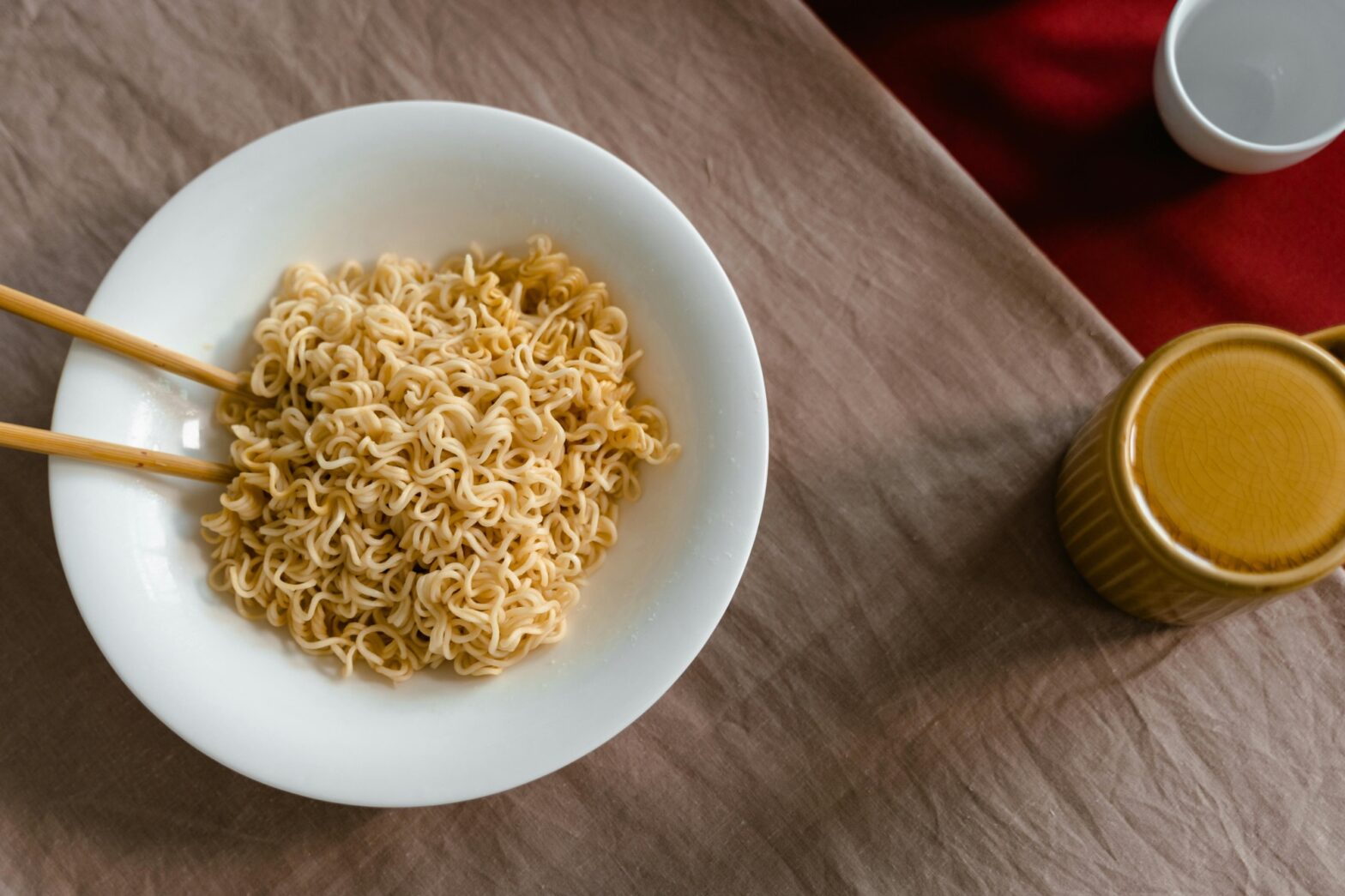 A bowl of noodles with a mug.